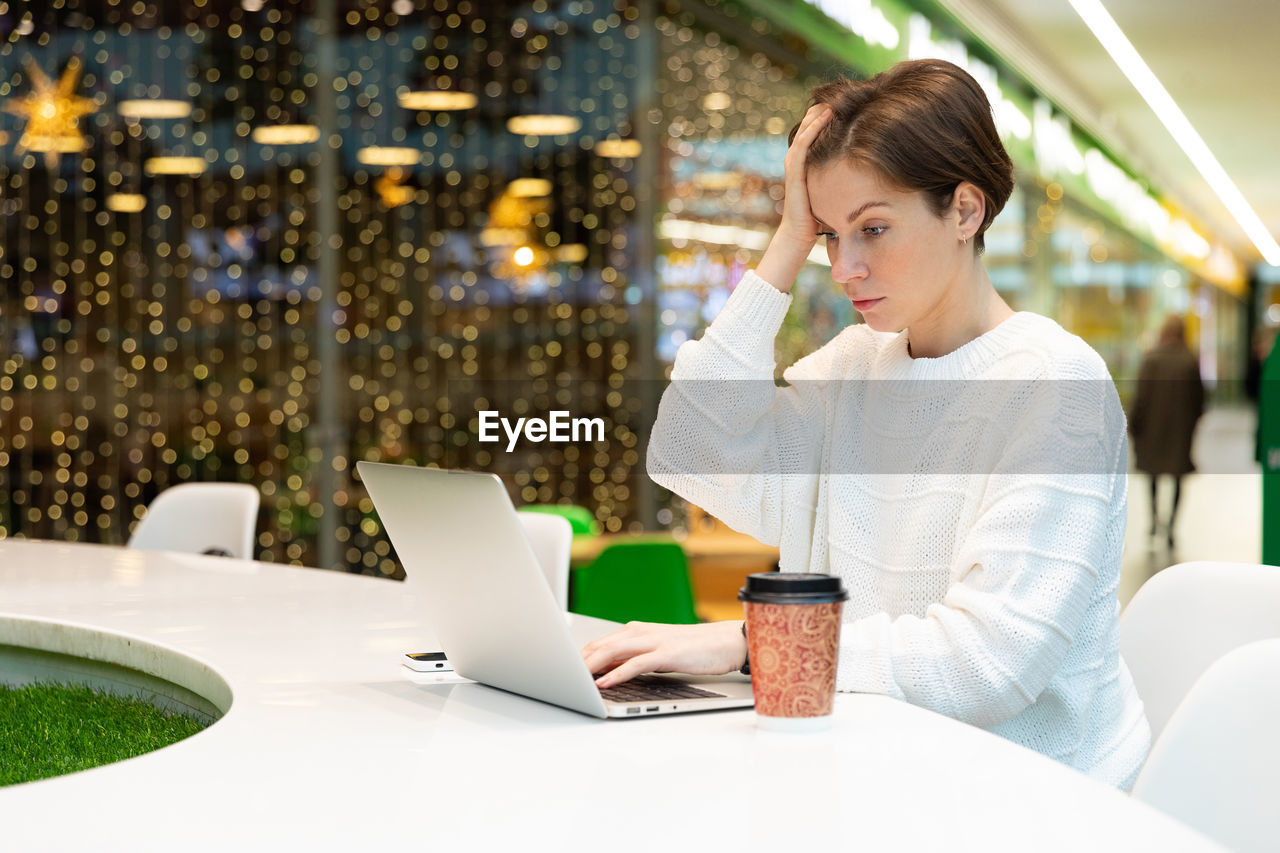 Frustrated woman using laptop in shopping mall