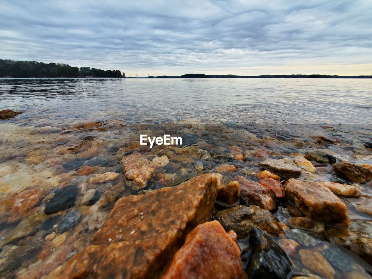 SURFACE LEVEL OF ROCKS ON SHORE AGAINST SKY