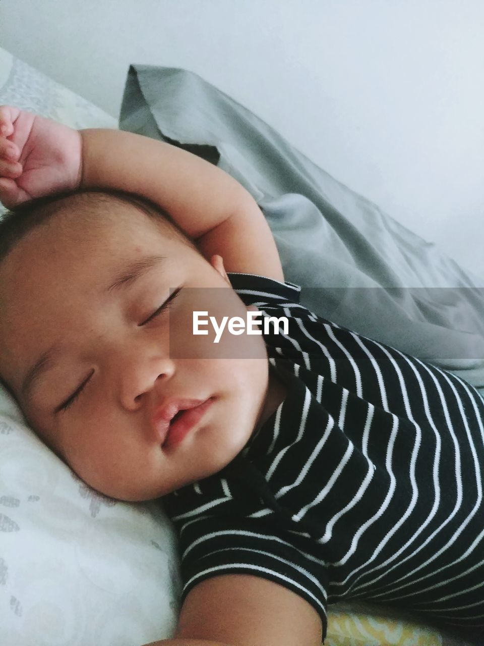 Cute baby boy lying on bed at home