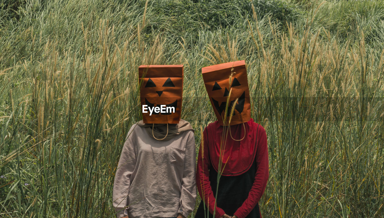 Women wearing shopping bags on head while standing on field