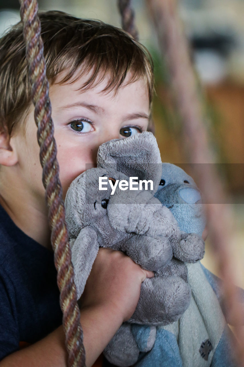 Portrait of cute boy with stuffed toys sitting on swing