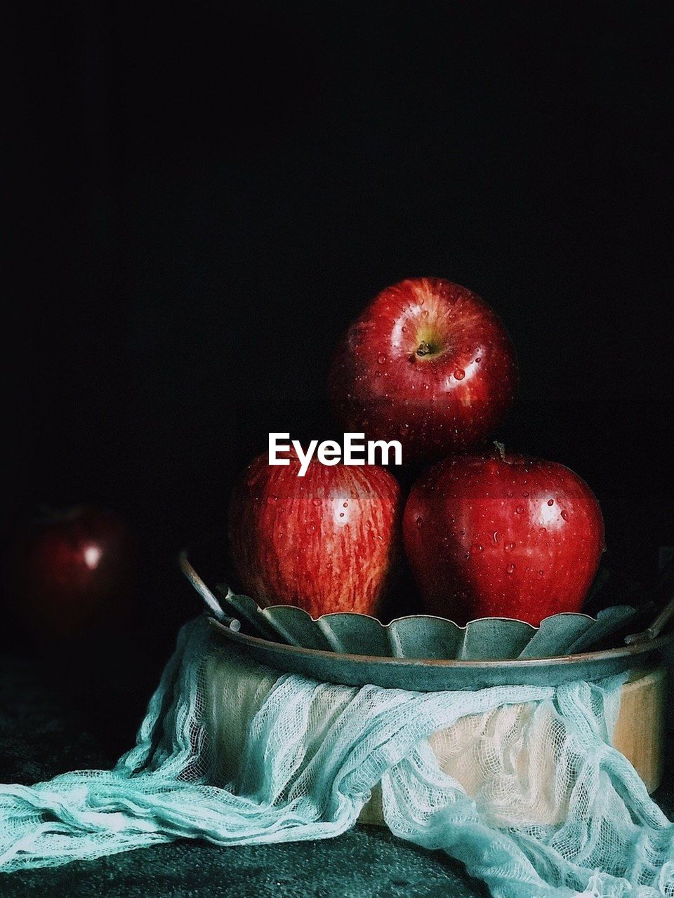 Close-up of apples in basket on table against black background