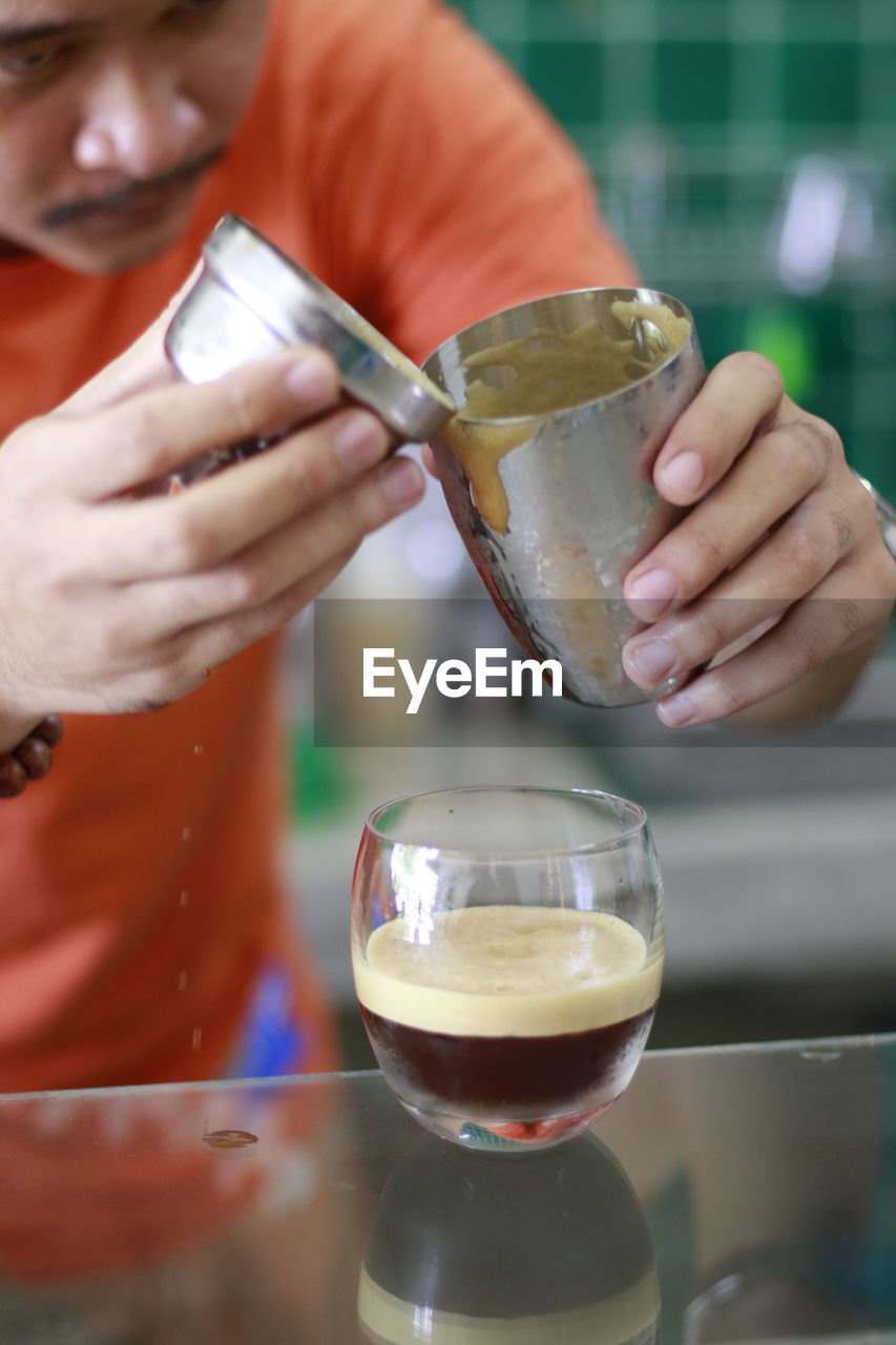 CLOSE-UP OF HAND POURING TEA IN GLASS