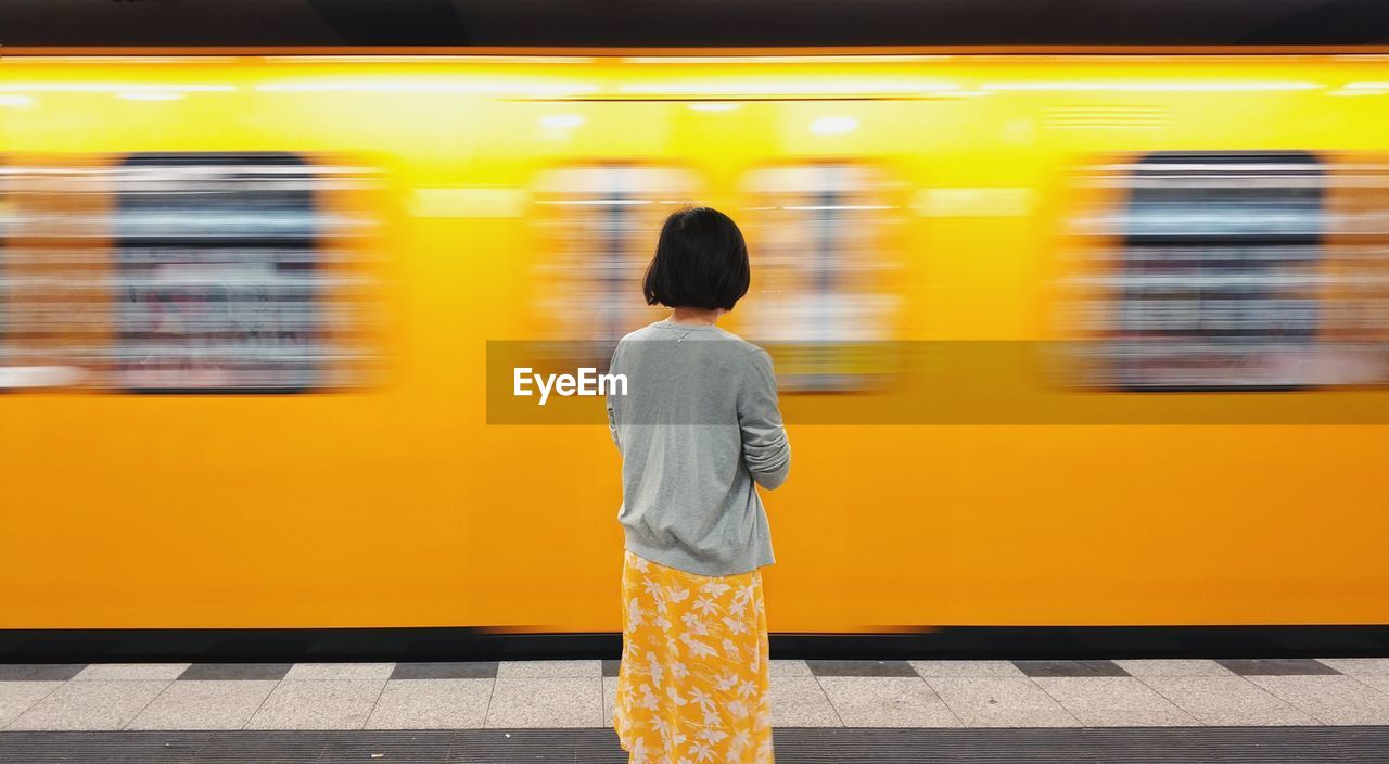 Rear view of woman standing at railroad station