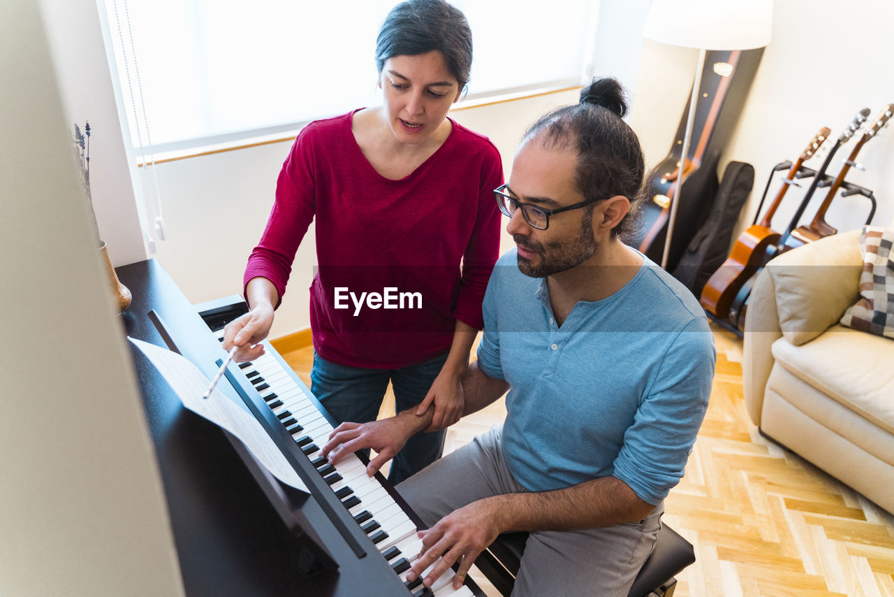 Man and woman using piano at home