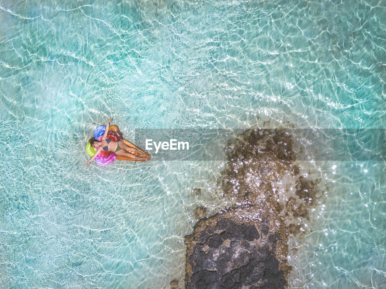 HIGH ANGLE VIEW OF WOMAN SWIMMING IN POOL AT SEA