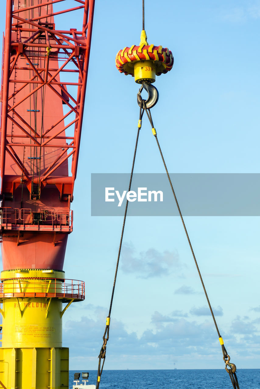 An offshore pedestal crane on board a construction work barge performing a lifting of an anchor 