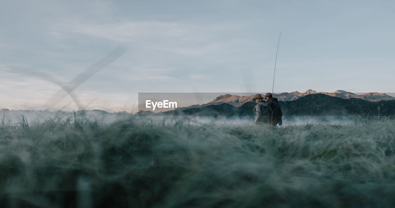 Man standing on field against sky flyfishing