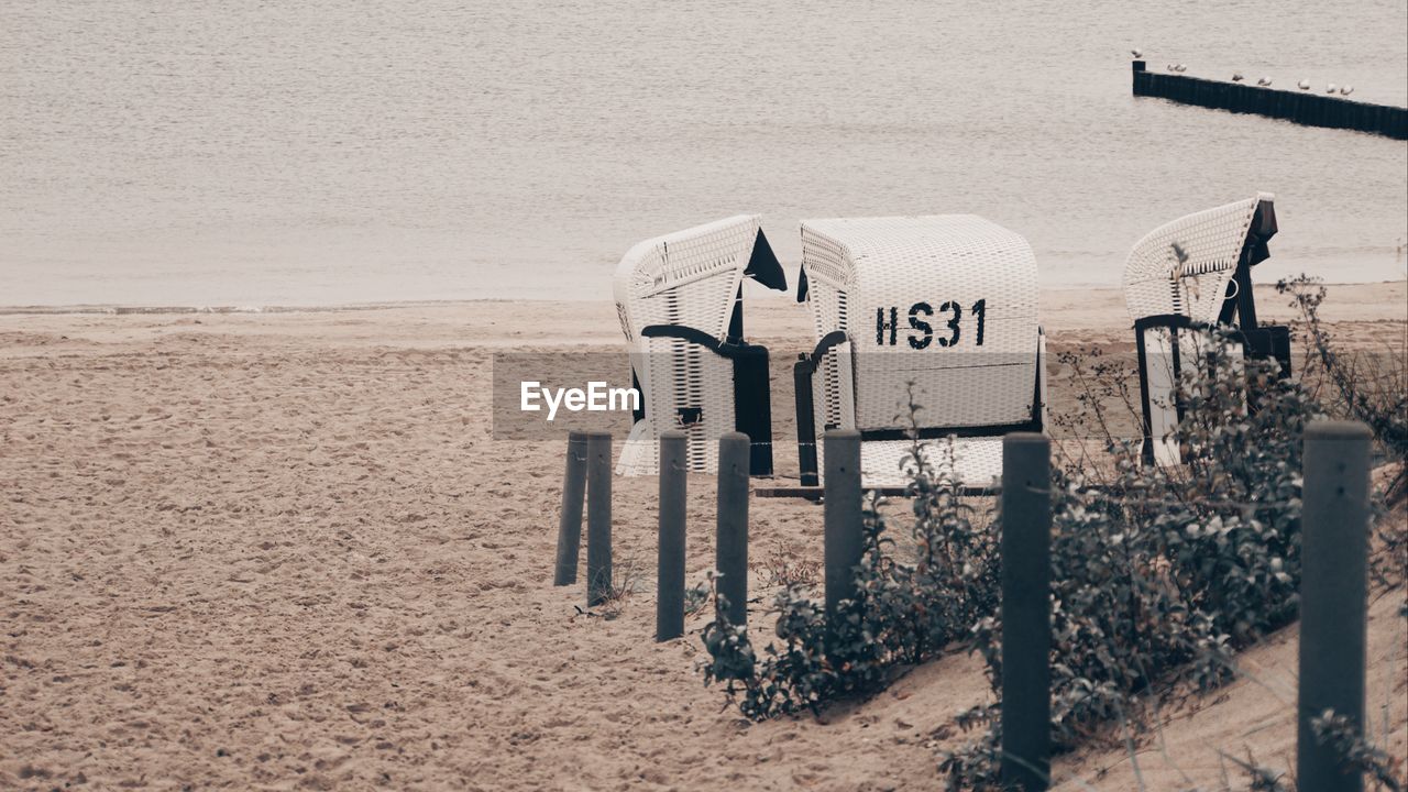 HOODED BEACH CHAIRS ON SAND AGAINST SEA