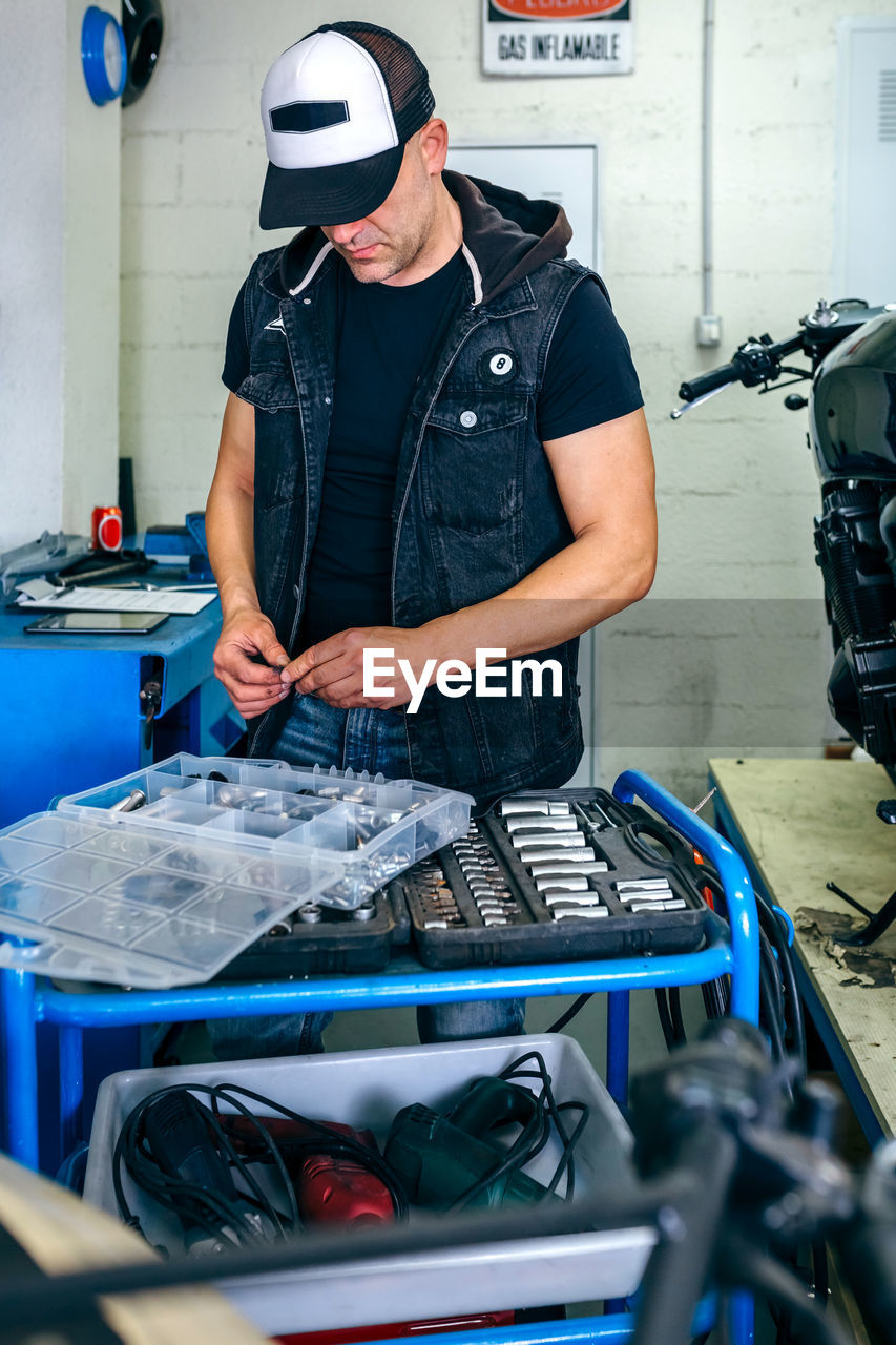 Mechanic holding with equipment and work tools in garage
