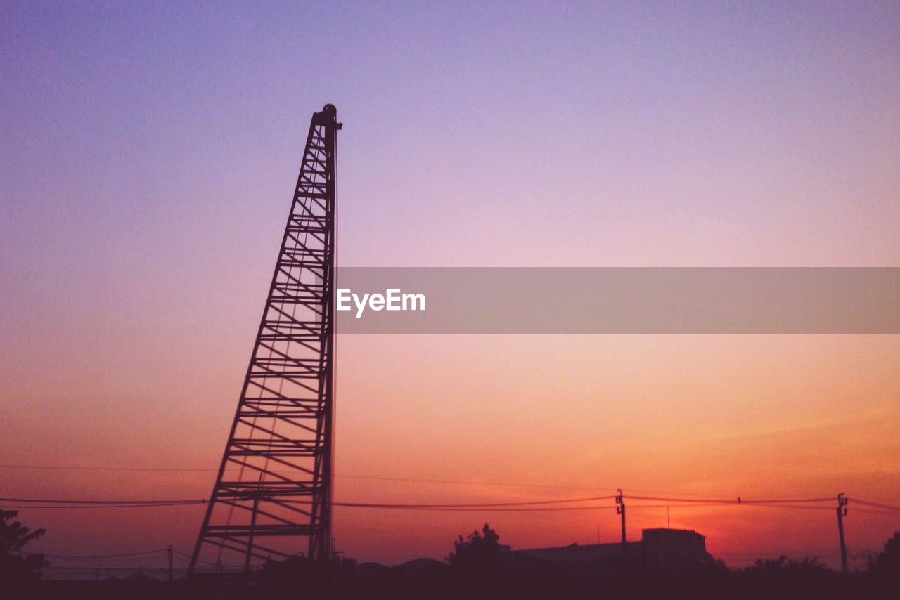 Low angle view of electricity pylon at sunset