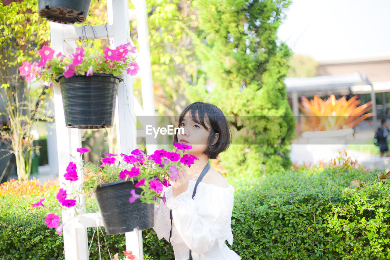 Young woman standing by flower pot in park