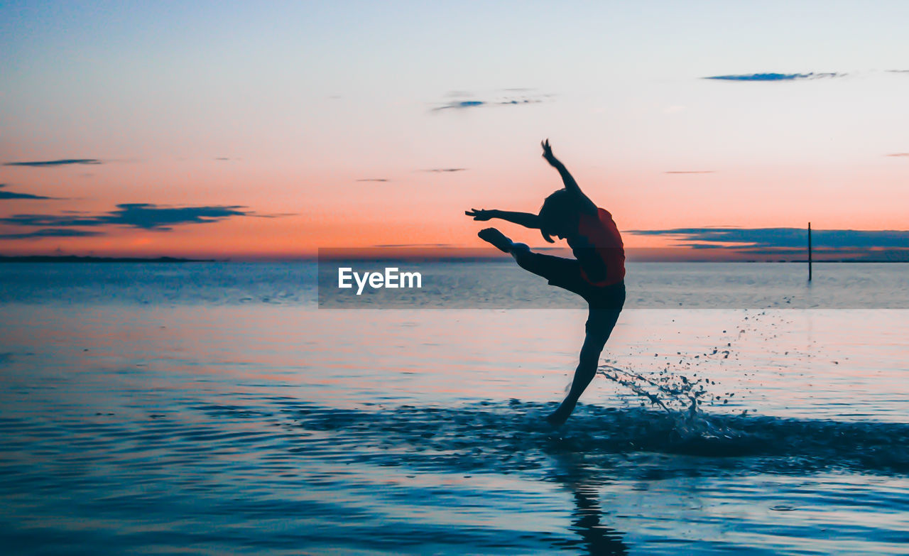 Boy jumping at sea during sunset