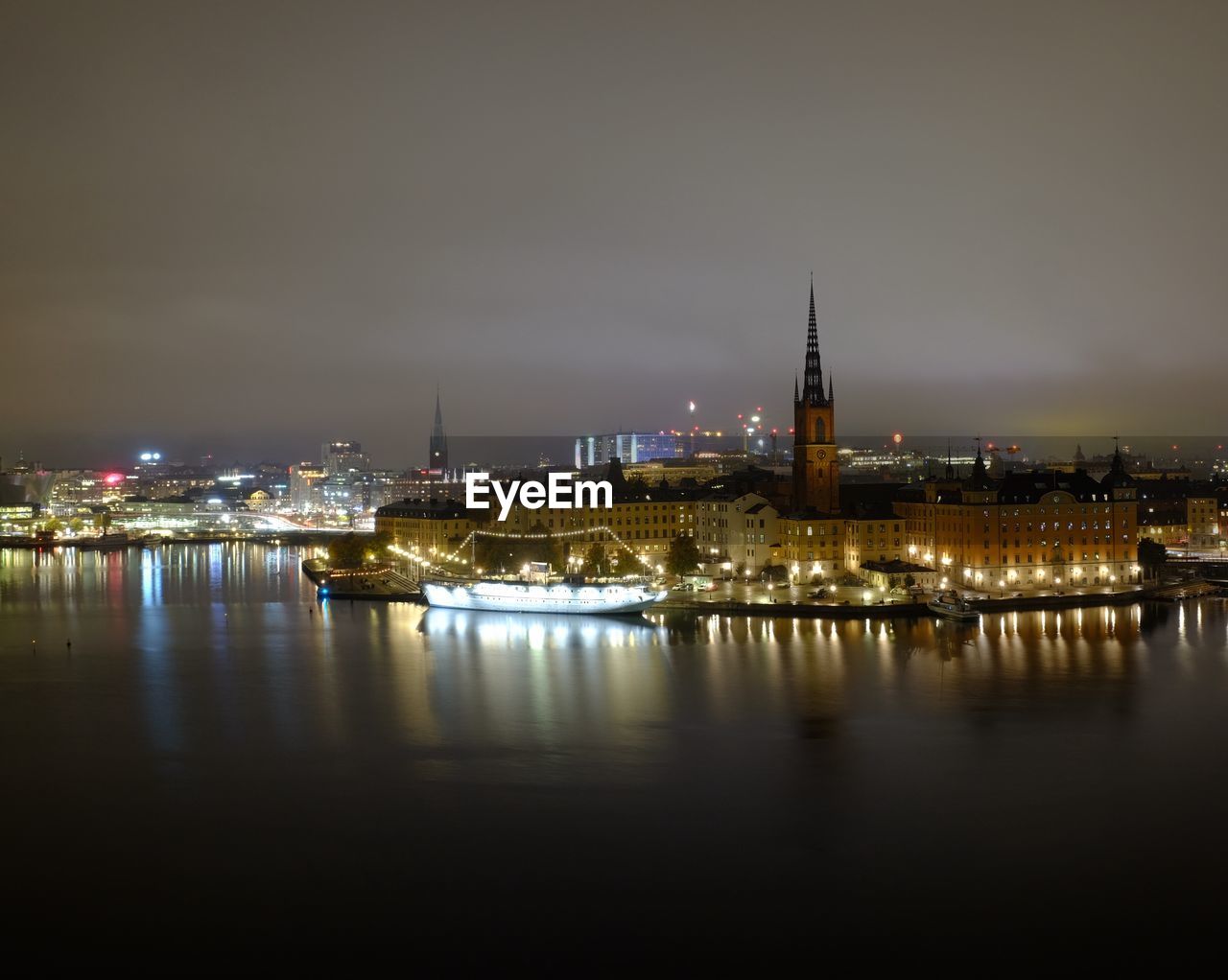 RIVER BY ILLUMINATED BUILDINGS AGAINST SKY AT NIGHT