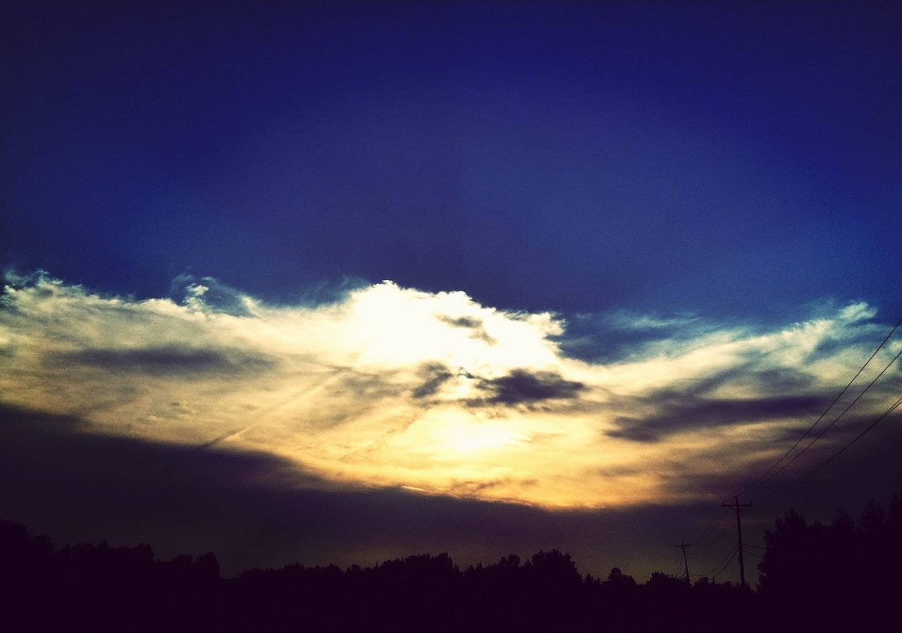 View of blue sky at dusk with yellow sun reflection in cloud