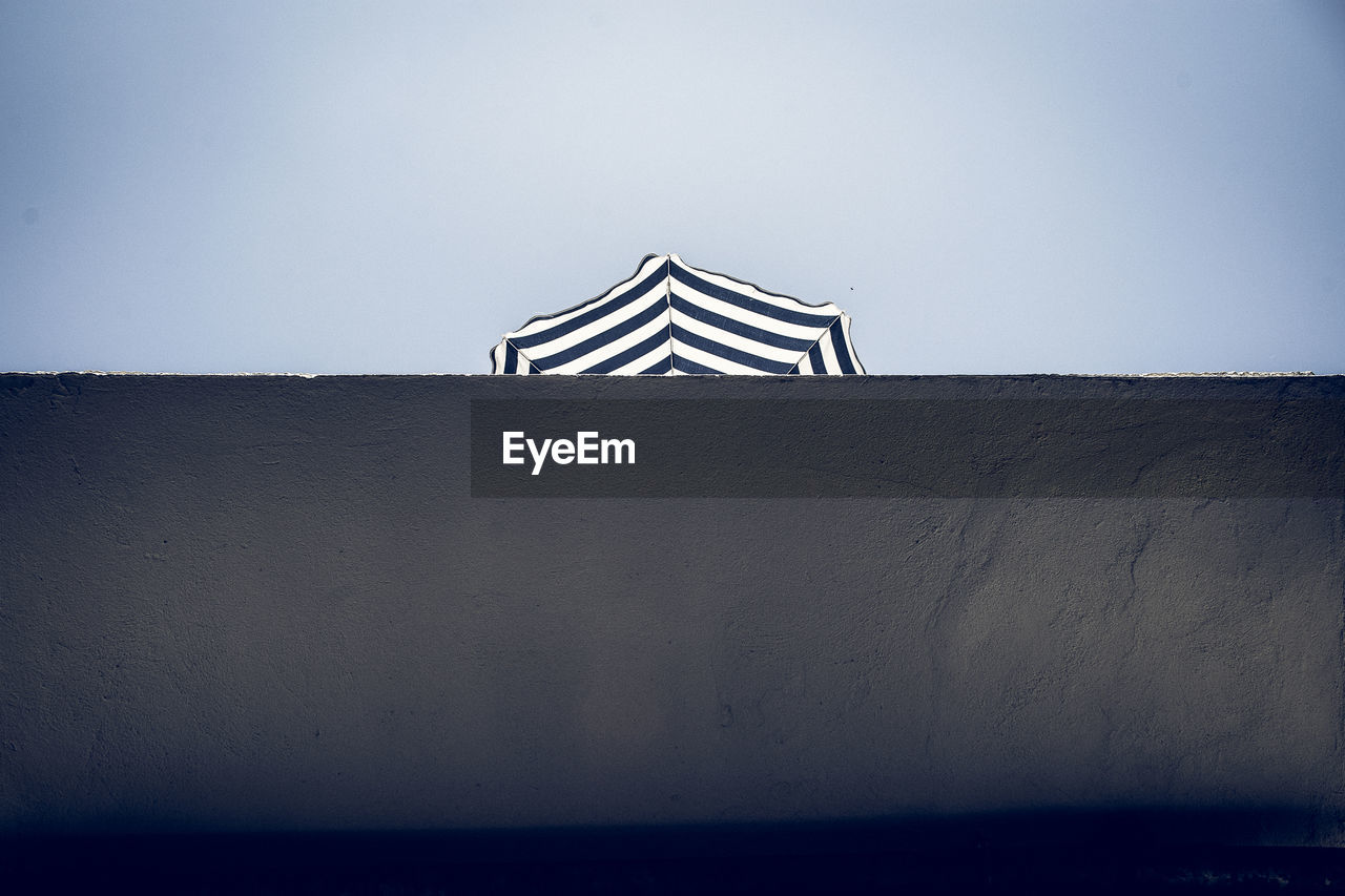 Low angle view of umbrella on wall against clear sky