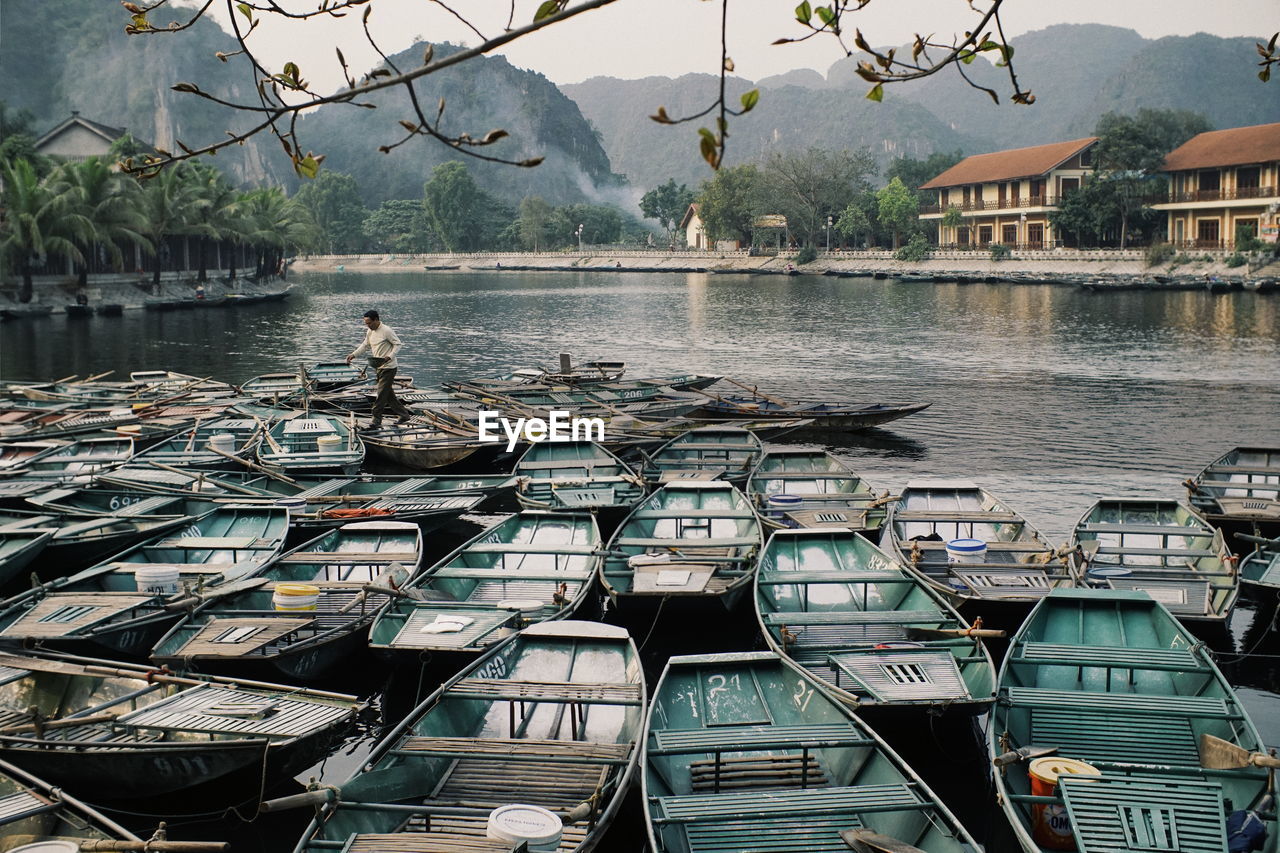 BOATS MOORED AT LAKE BY BUILDINGS