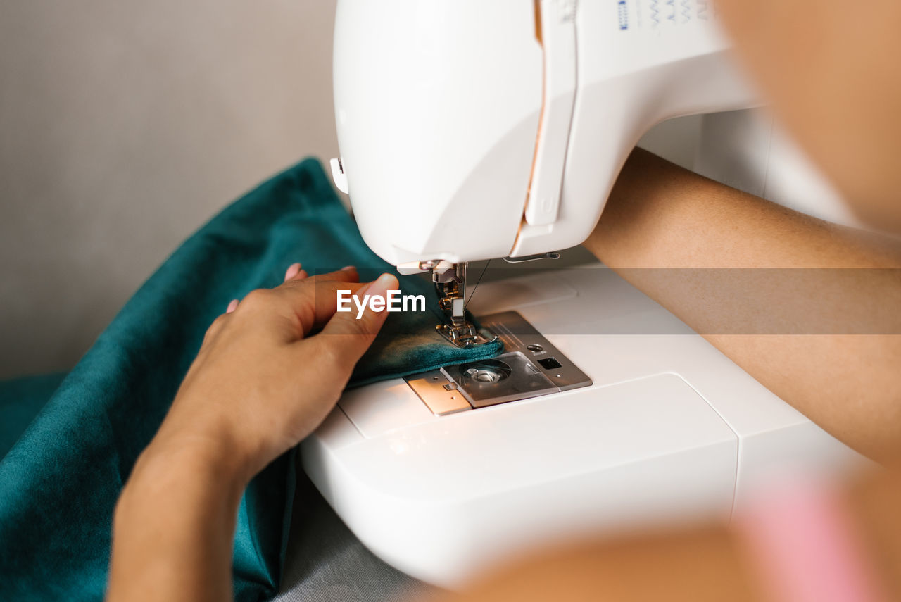 Hands in the process of sewing. women's hands sew fabric on a hobby typewriter at home.