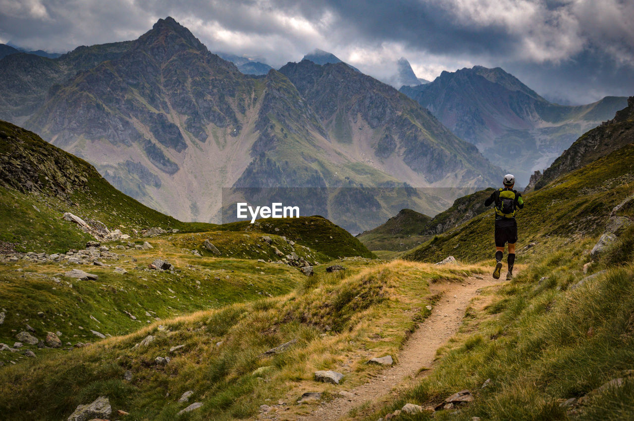 Rear view of man walking on mountains against sky