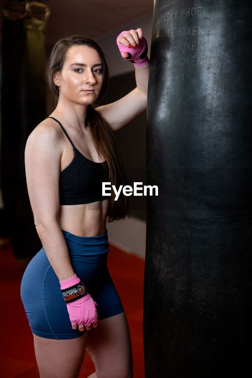 FULL LENGTH OF YOUNG WOMAN STANDING AGAINST PINK