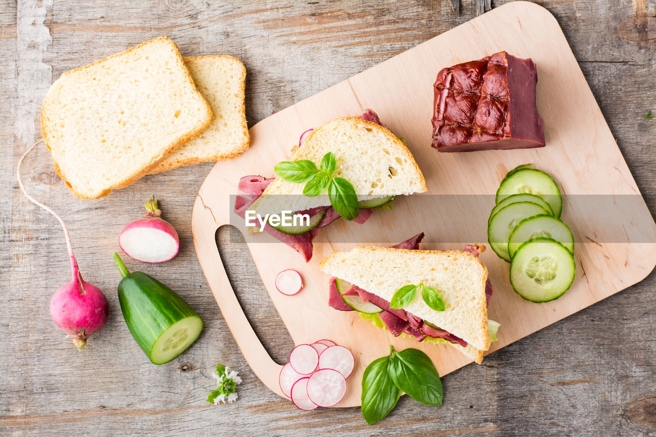 Fresh sandwiches with pastrami, cucumber and radish on a cutting board. american snack
