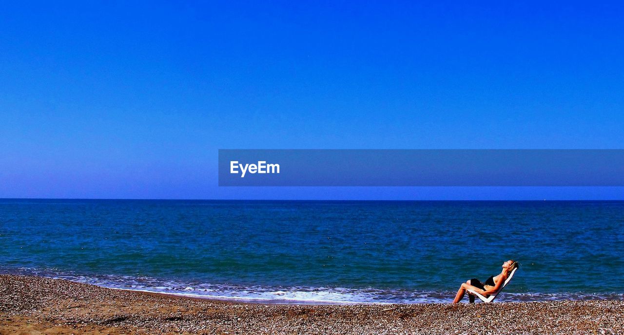 Woman on beach against clear blue sky