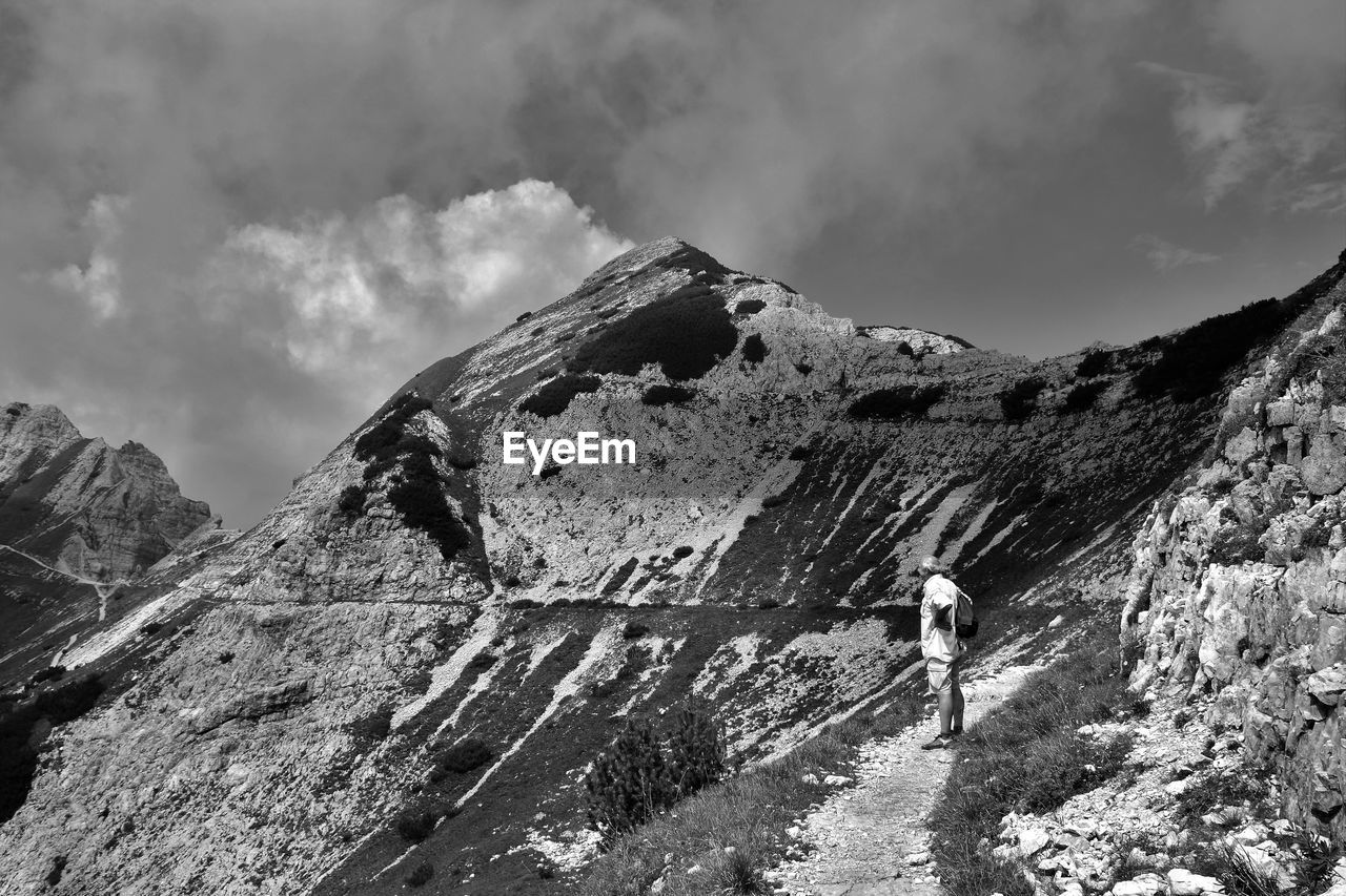 Man standing on rock by mountain against sky