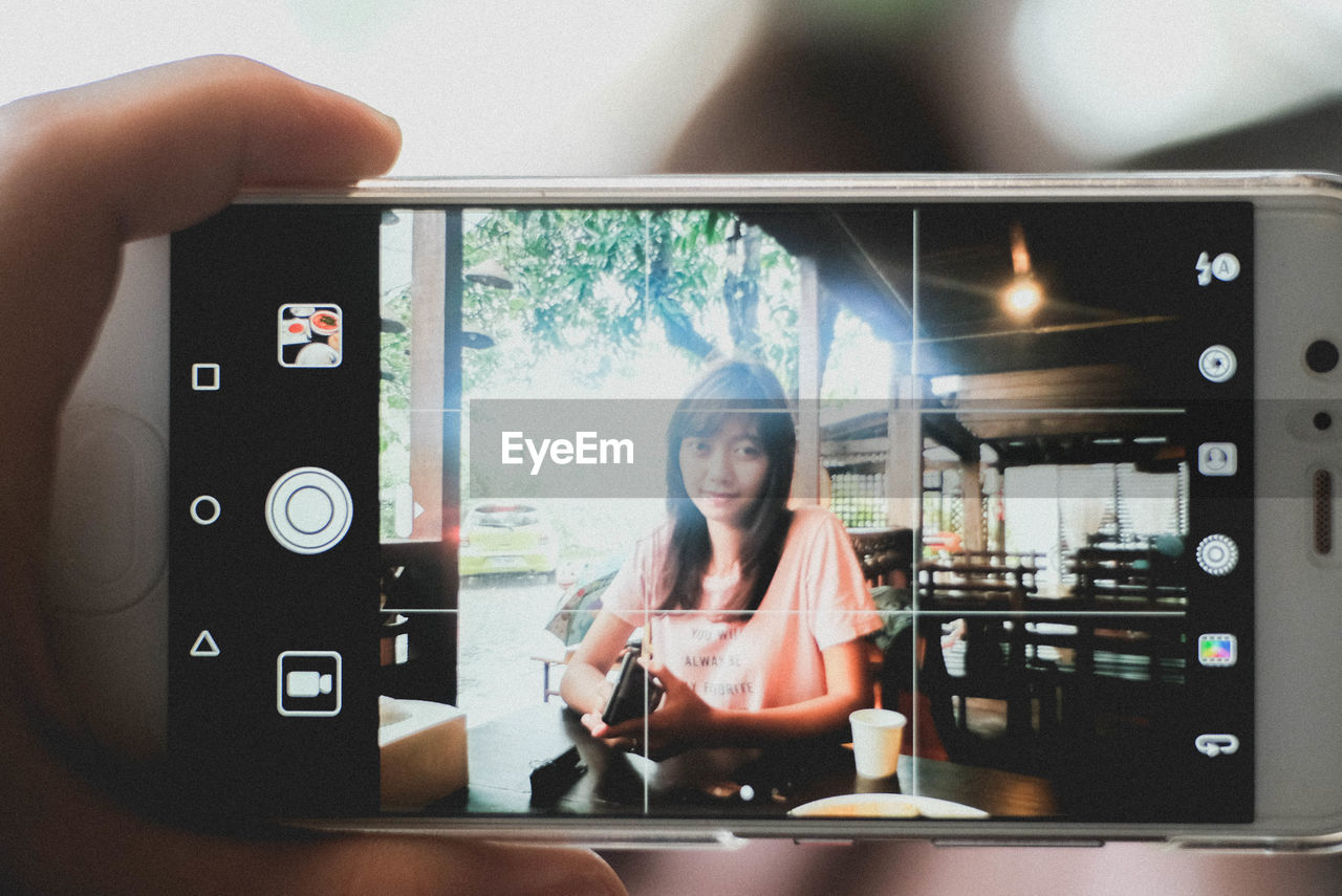 PORTRAIT OF SMILING WOMAN PHOTOGRAPHING WHILE USING PHONE