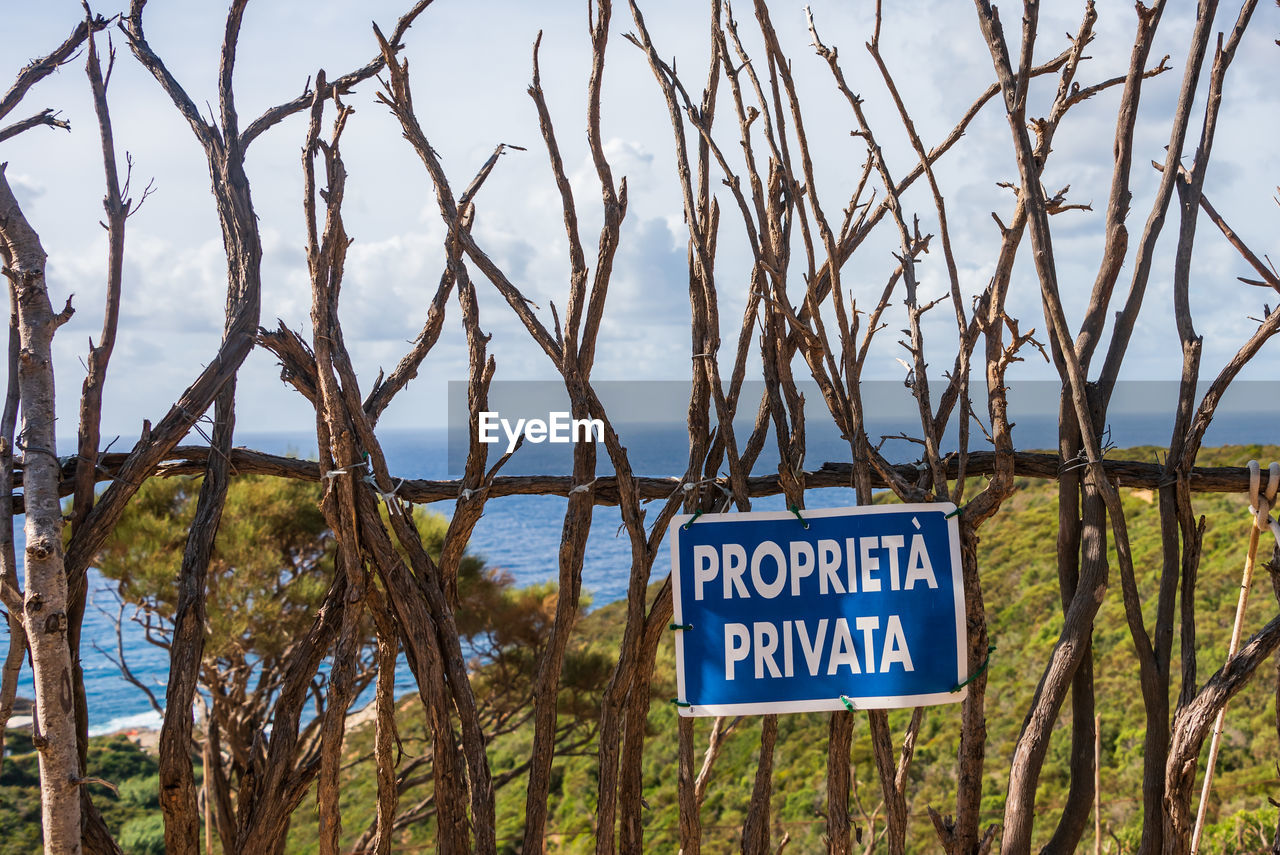 sign, communication, text, plant, western script, nature, tree, no people, information sign, day, warning sign, sky, land, outdoors, grass, tranquility, guidance, non-urban scene, blue, travel destinations, landscape, water, branch, beauty in nature