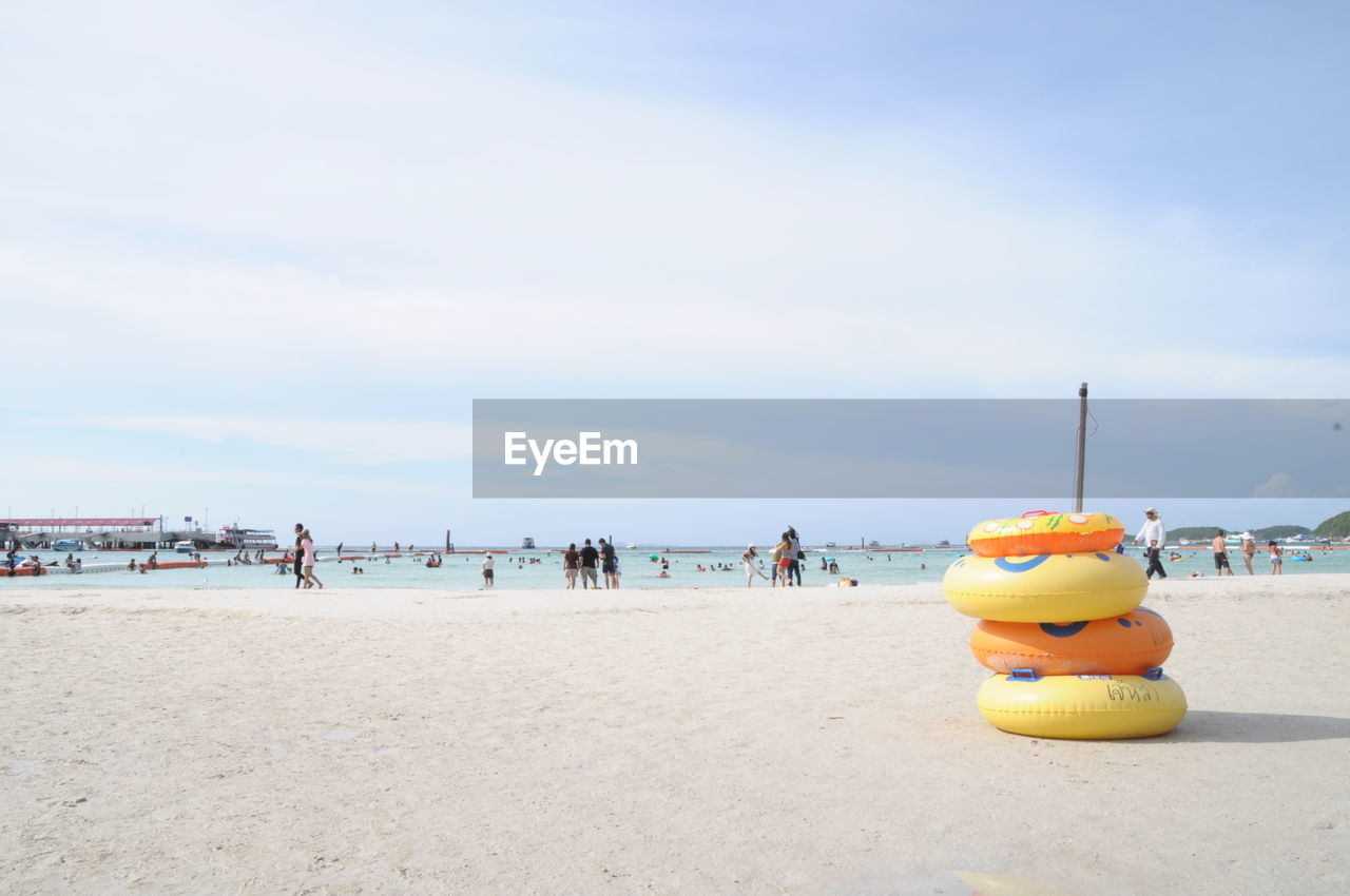 Stack of inflatable rings on shore against cloudy sky