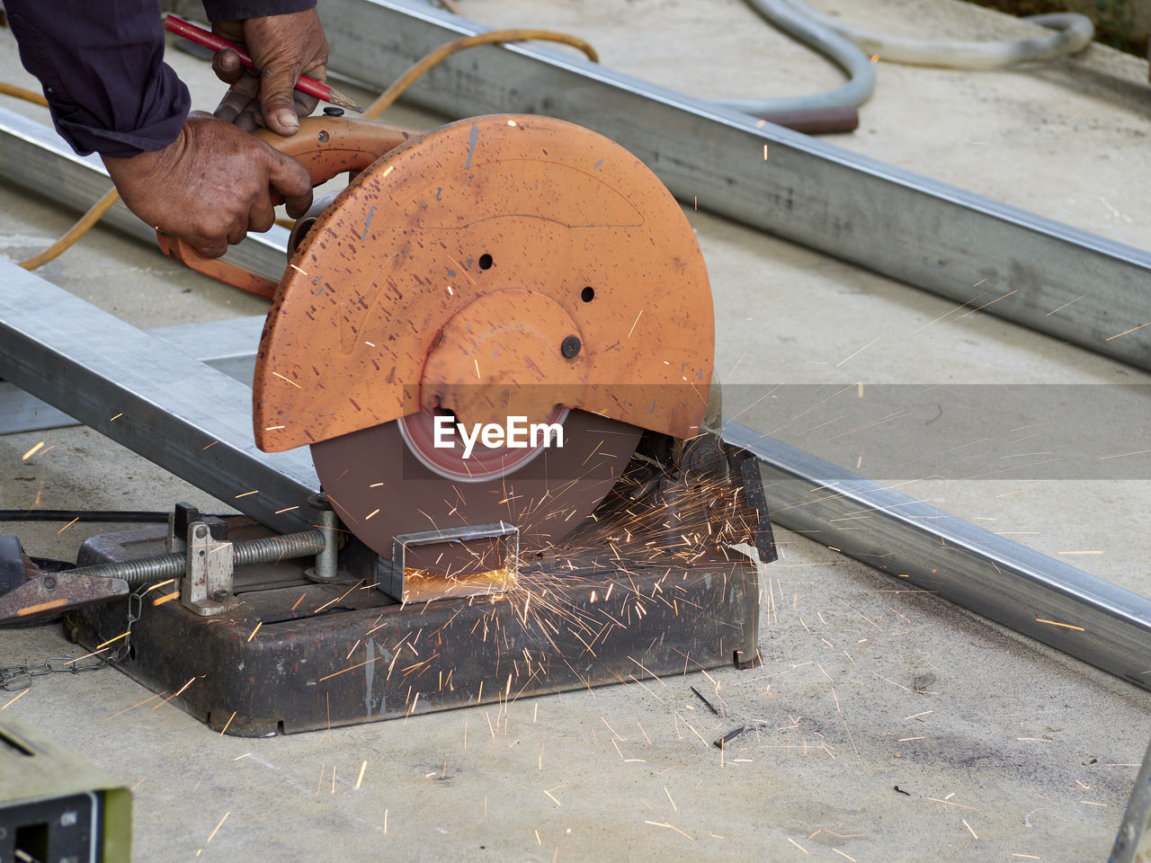 Cropped hands of man cutting metal with circular saw