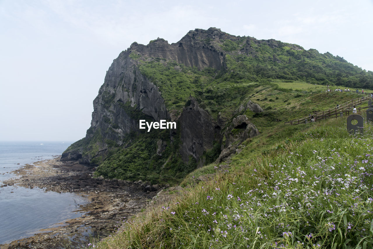 Scenic view of cliff by sea against sky