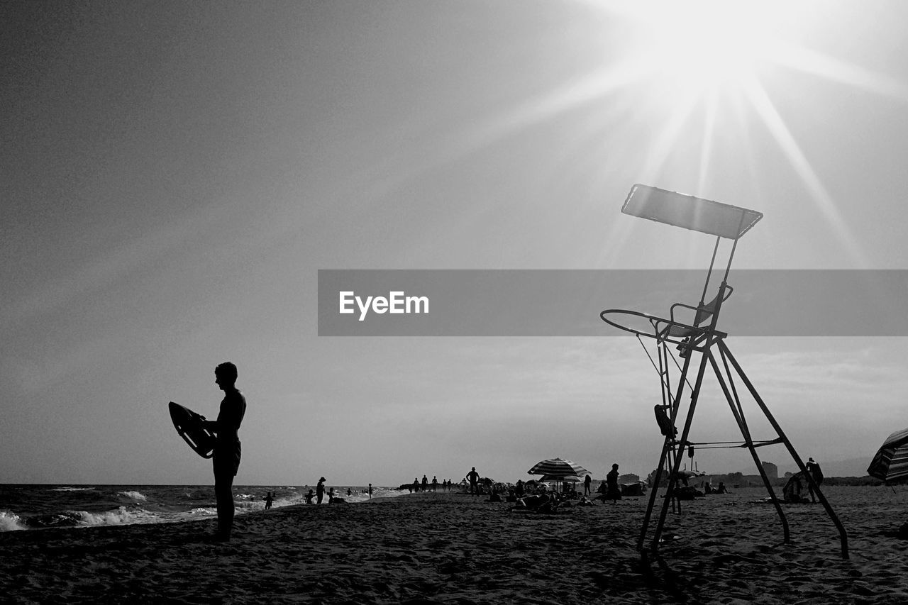 Man by lifeguard chair on beach against sky