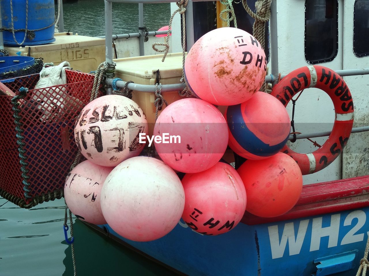 Close-up of buoys and inflatable ring hanging on fishing boat