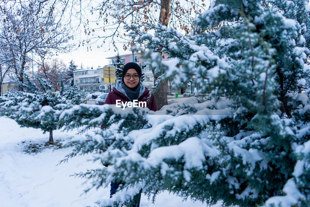 Portrait of smiling woman standing in snow covered park