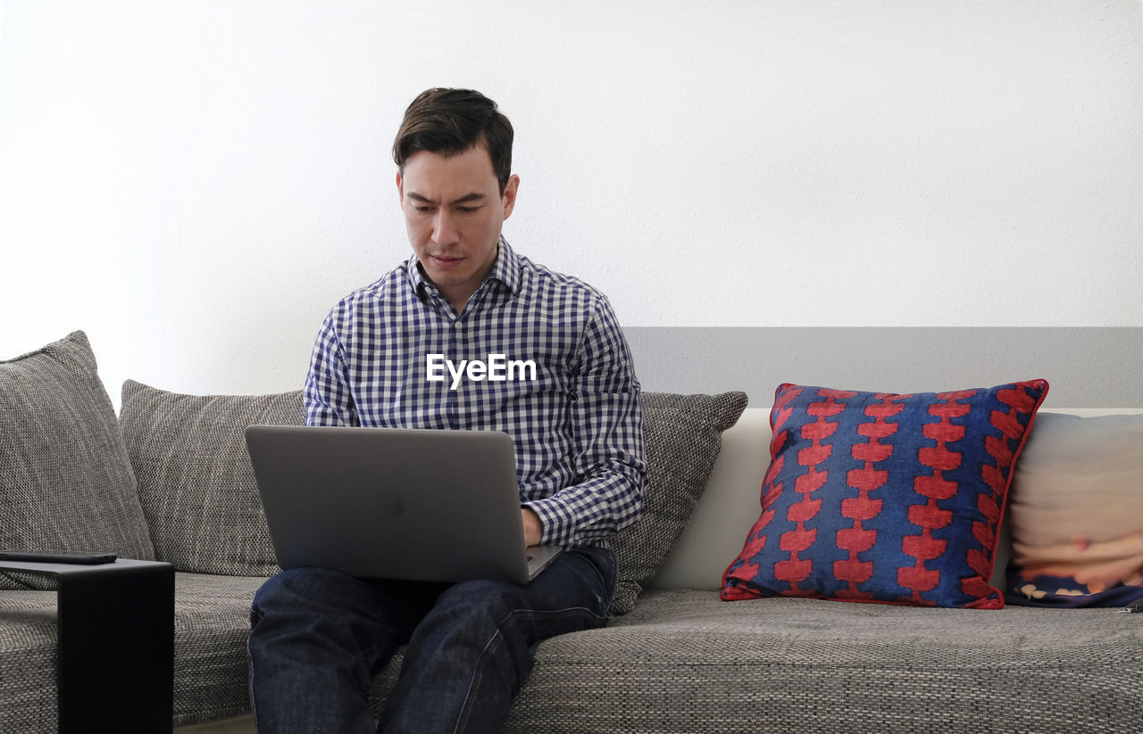 Man using laptop while sitting on sofa at home