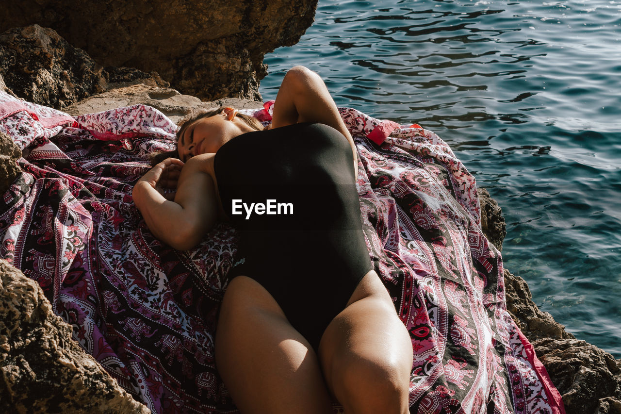 High angle view of woman wearing sunglasses lying on rock formation