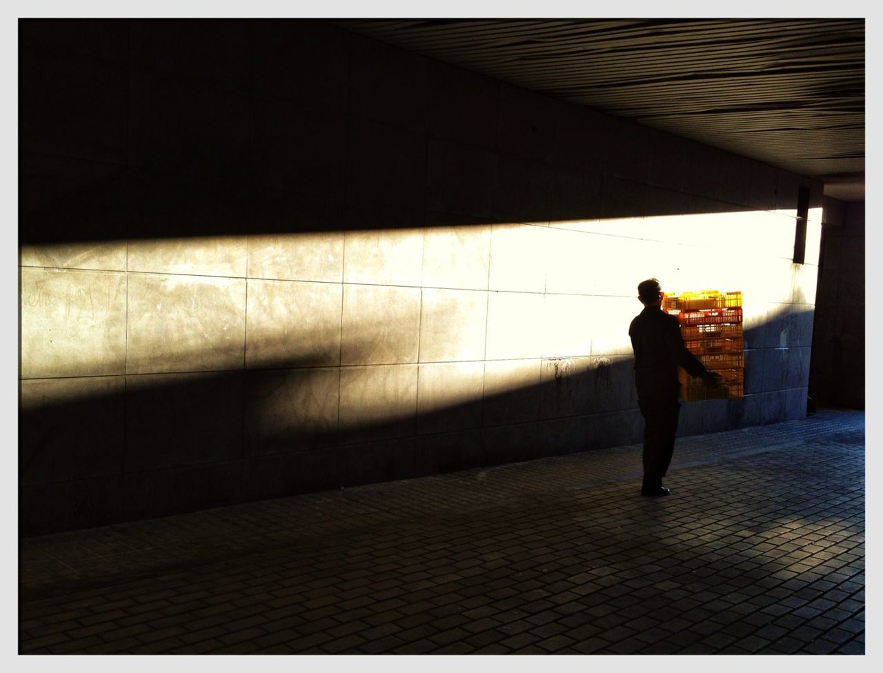 Silhouette man carrying crate in tunnel