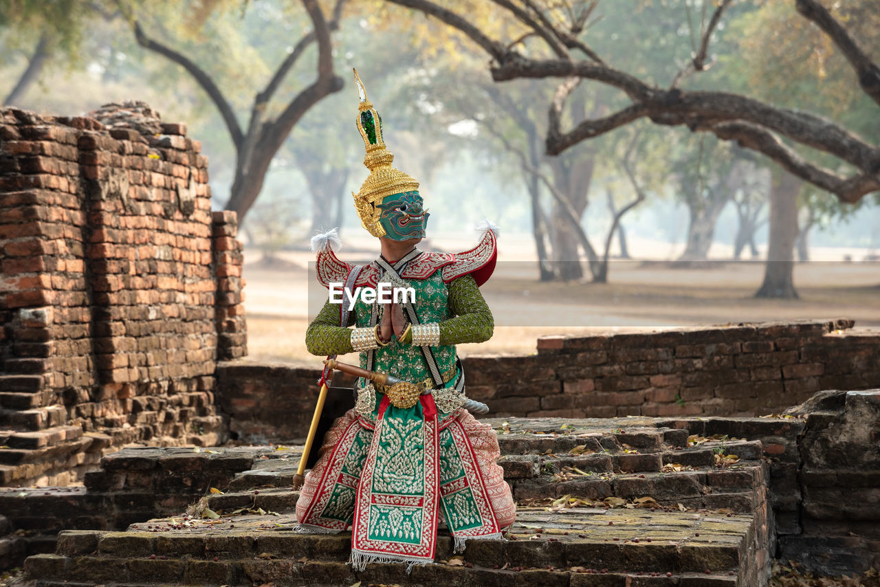 BUDDHA STATUE BY TREE OUTSIDE BUILDING