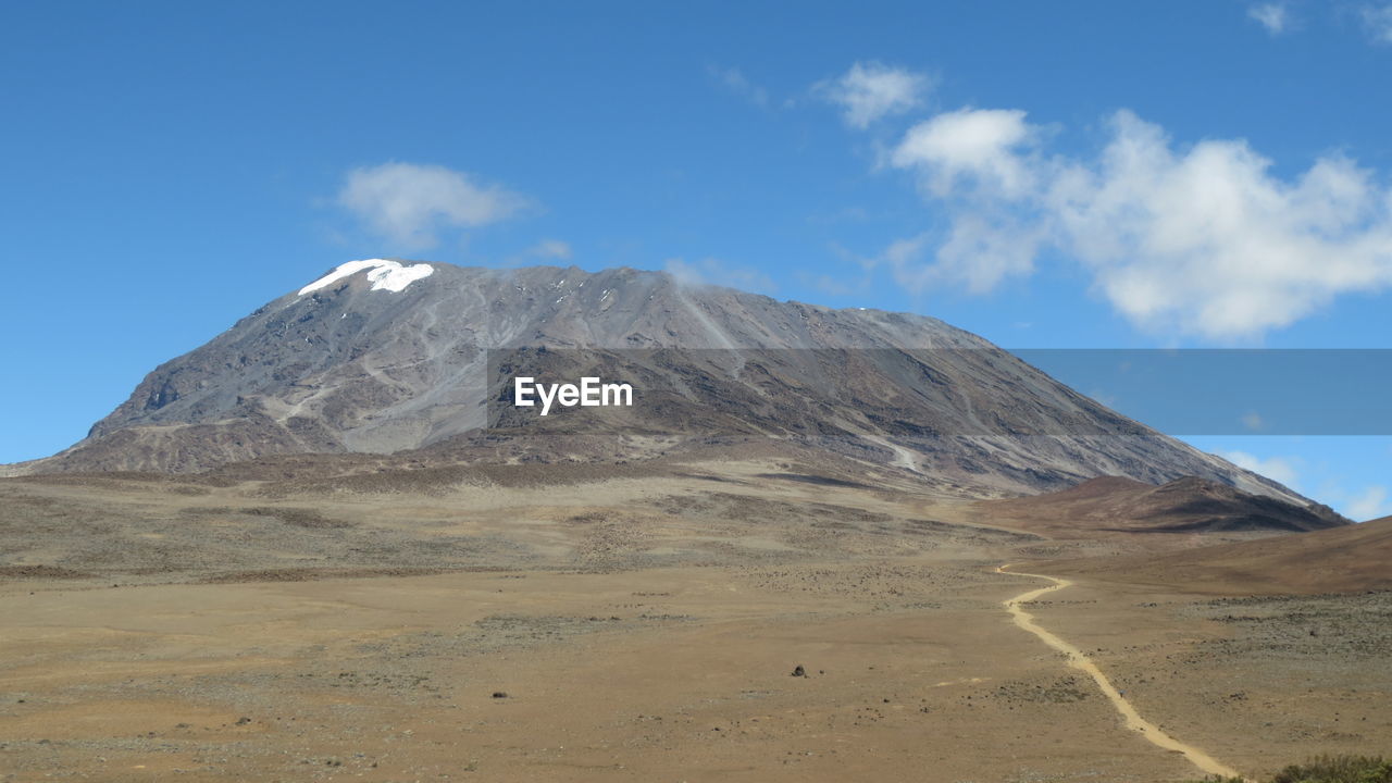 Scenic view of volcanic mountain against blue sky