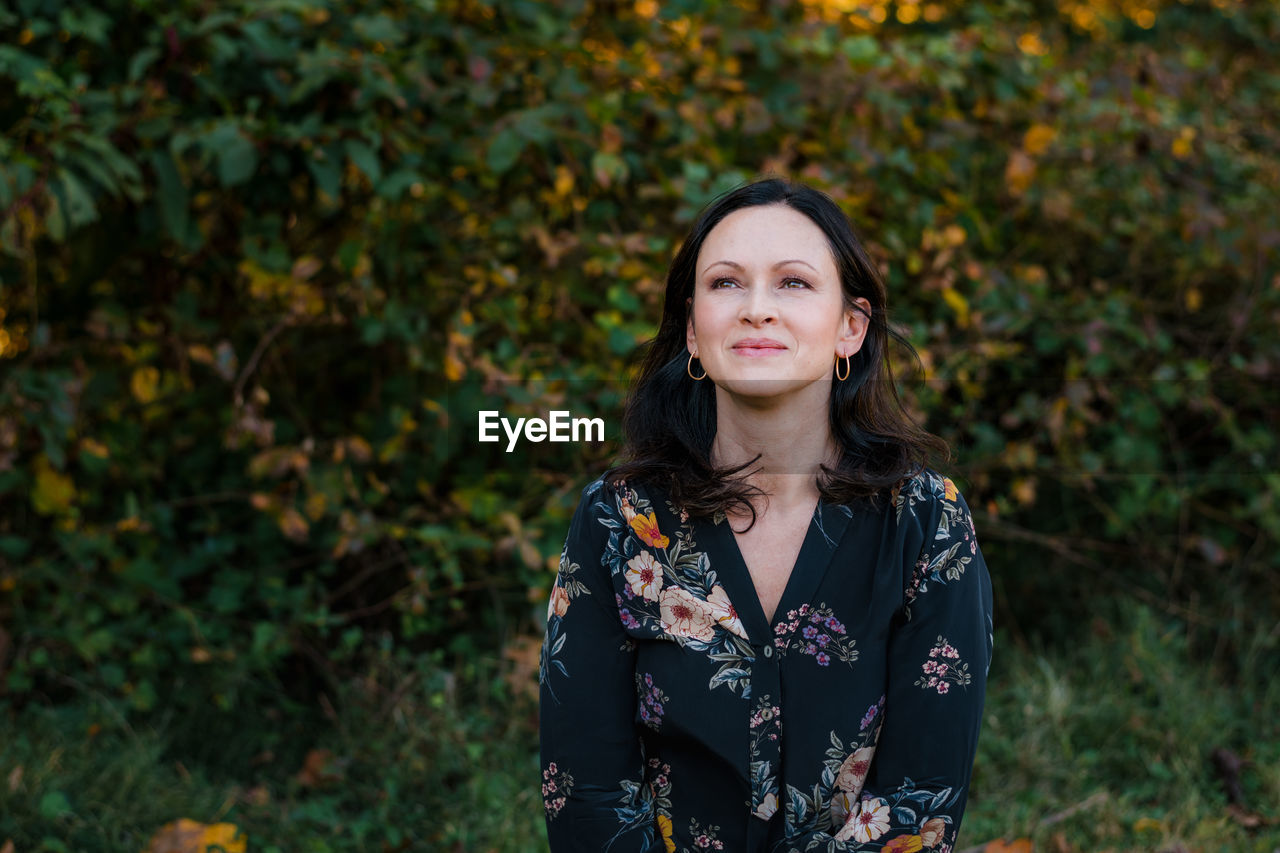 Portrait or brunette woman in 40s outside looking off camera