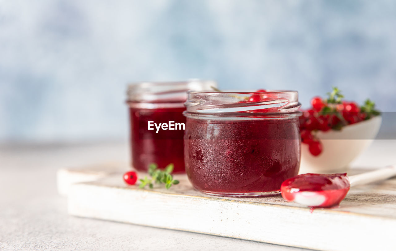 Homemade red currant jam or jelly in glass jars and red currants fresh berries.