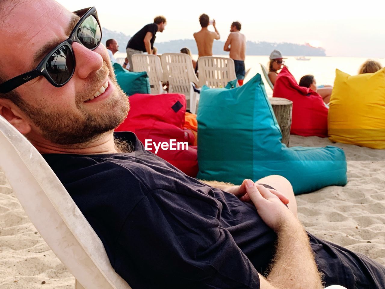 Smiling man wearing sunglasses while resting at beach