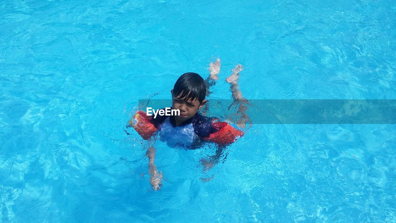 High angle view of boy wearing water wings swimming in pool