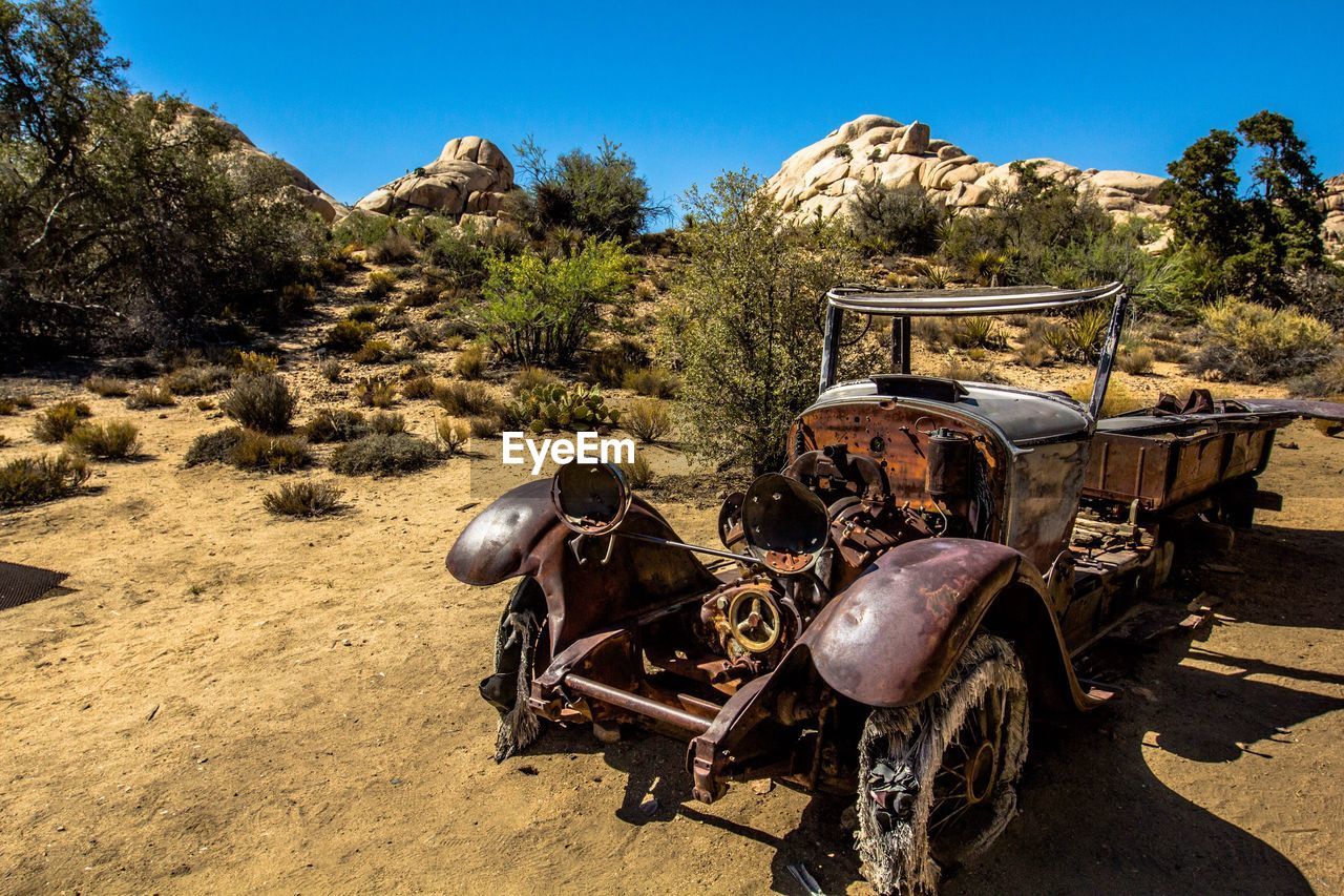 Abandoned truck on field against clear blue sky