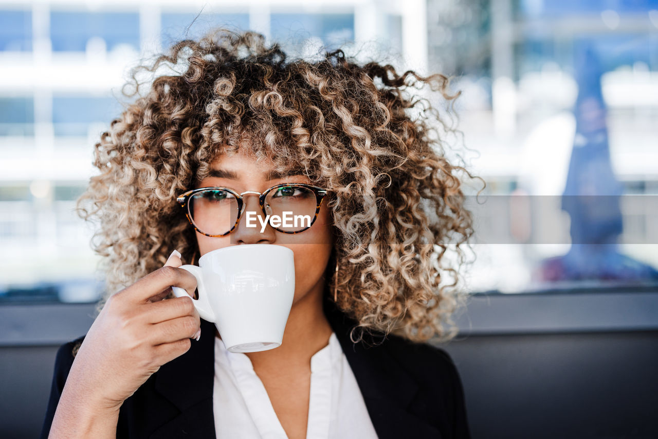 Beautiful hispanic afro business wearing eye glasses drinking coffee in cafeteria. business concept