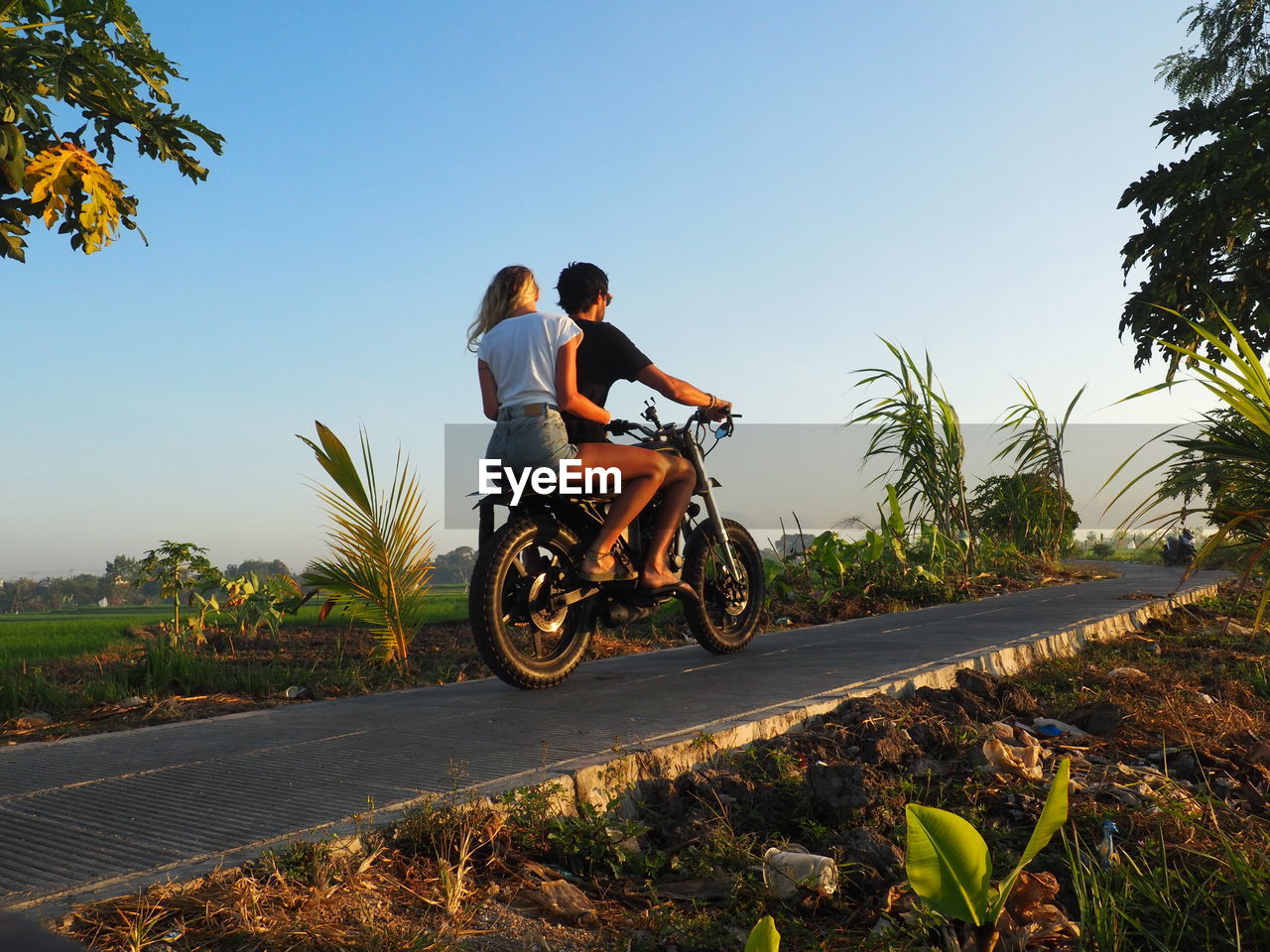 Man with girlfriend riding motorcycle on road against clear sky