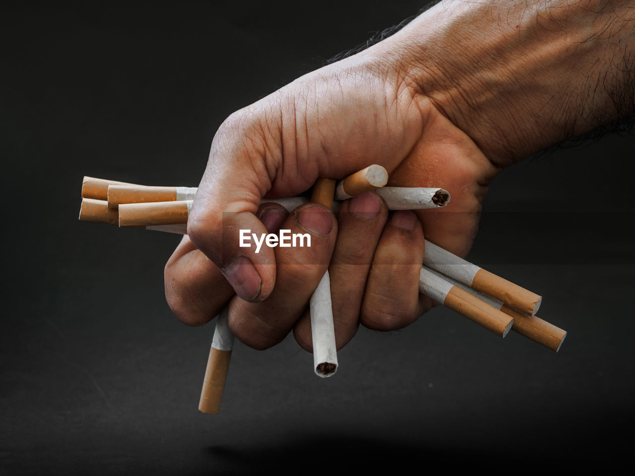 Cropped hand of person crushing cigarettes over table