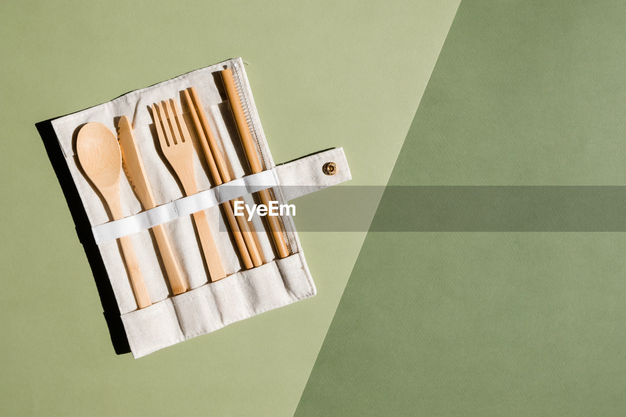 Set of eco friendly bamboo cutlery on green background. sustainable lifestyle. plastic free concept.