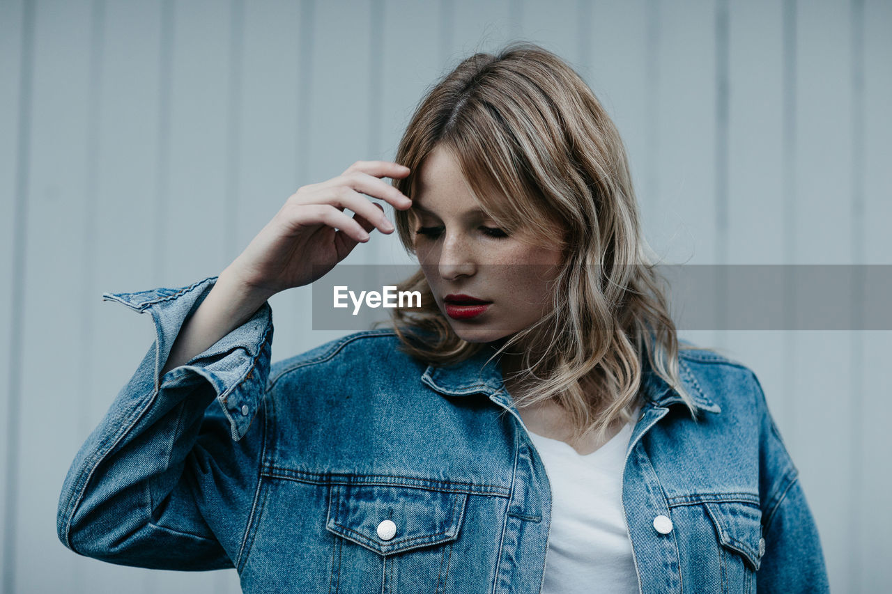 Thoughtful woman wearing denim jacket while standing outdoors